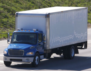 a box truck with a blue cab and white box traveling on a highway