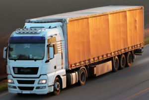 a cab-over truck with a white cab at dusk