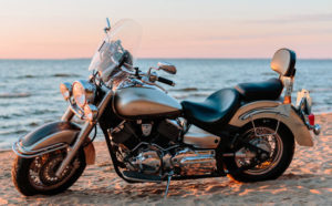 silver classic cruiser motorcycle on a sandy beach by the water