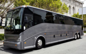 gray coach bus parked in front of a historic building