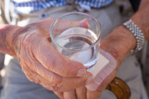 dehydrated elderly lady holding an almost empty glass of water needs help of a dehydration abuse attorney