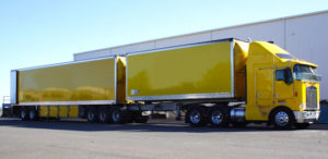 yellow doubles truck parked next to a warehouse