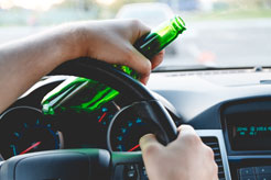 a man with a bottle of beer in his hand driving a car