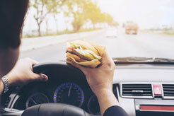 a man eating a hamburger while driving