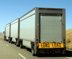 a long combination vehicle with white trailers on a highway