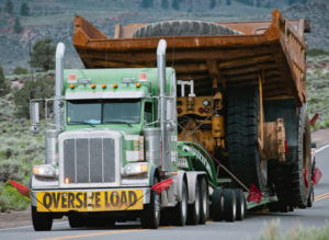 a lowboy truck carrying a huge dump truck on its trailer