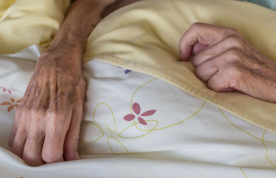 nursing home malnutrition attorney is ready to assist this malnourished elderly lady holding her hands on a blanket