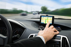 a man in a suit setting a navigation unit while driving his car