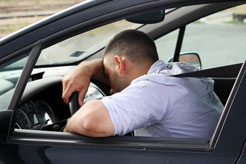 a young man asleep behind the wheel of his moving car