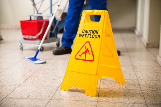 worker washing the floor with a warning sign helps to avoid lawsuits by the slip and fall lawyer Los Angeles trusts