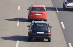 a blue car tailgating a red car on a freeway