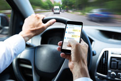 a man holding a smartphone and texting while driving