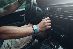 a man adjusting the controls of his car radio while driving