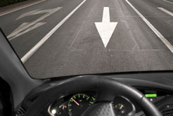 a car on a highway facing an arrow on the pavement showing that it is driving wrong way