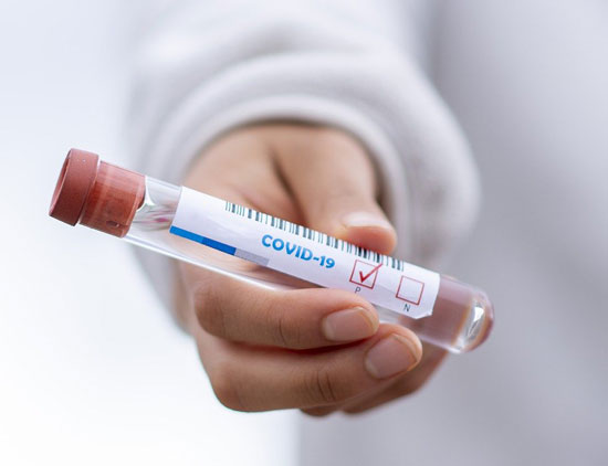 a nurse holding a positive COVID-19 test result tube