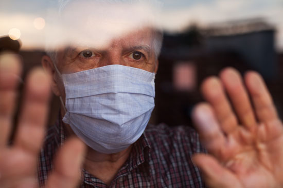 elderly man in a mask behind glass waiting for COVID-19 vaccine